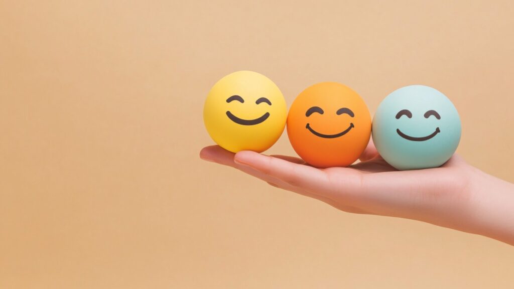 幸せと健康を表すために、3 つの笑顔の球体を優しく握っている手。