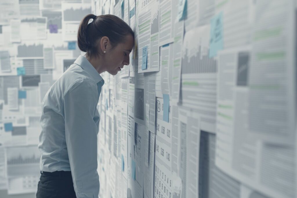 財務チャートで覆われた壁に寄りかかり、絶望感を感じている、疲れ果てて落ち込んでいるビジネスウーマン、ビジネス失敗のコンセプト