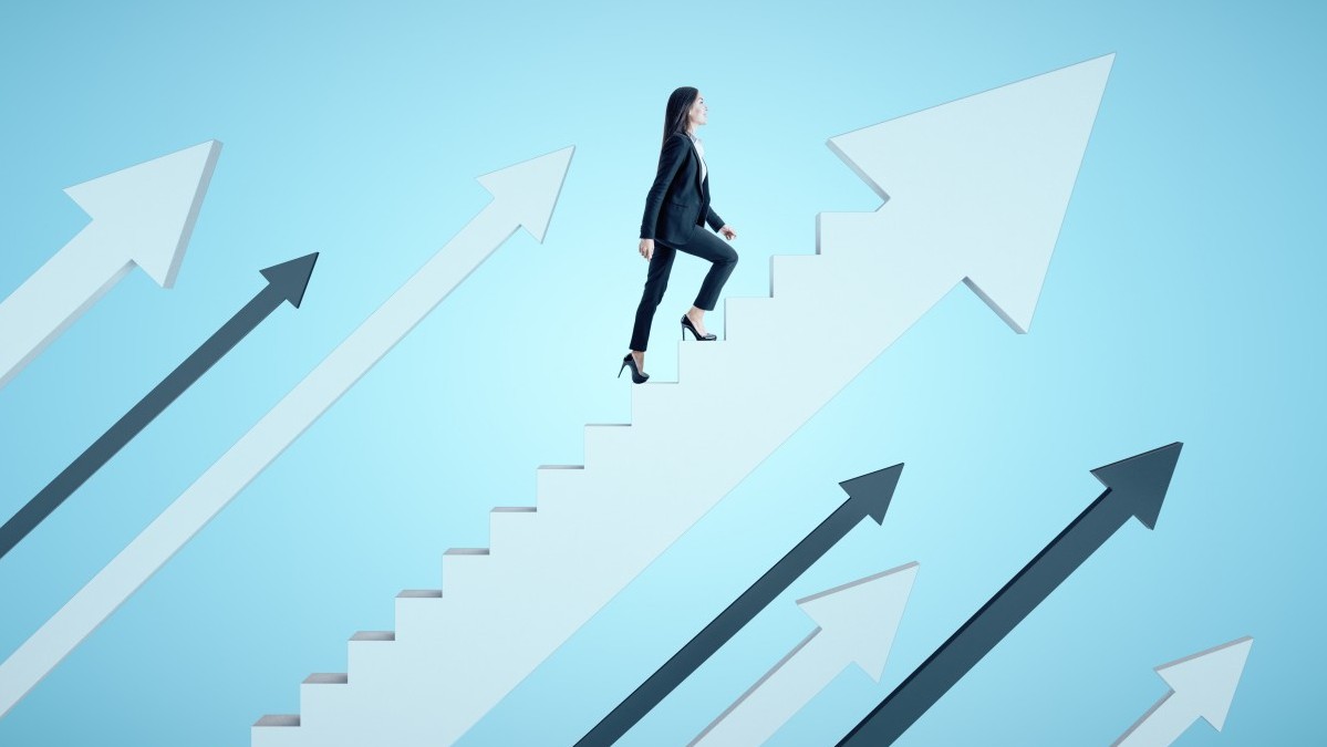 スーツを着たビジネスウーマンが、青い背景に白い矢印の形をした階段を登っています。成功とスタートアップのコンセプト。