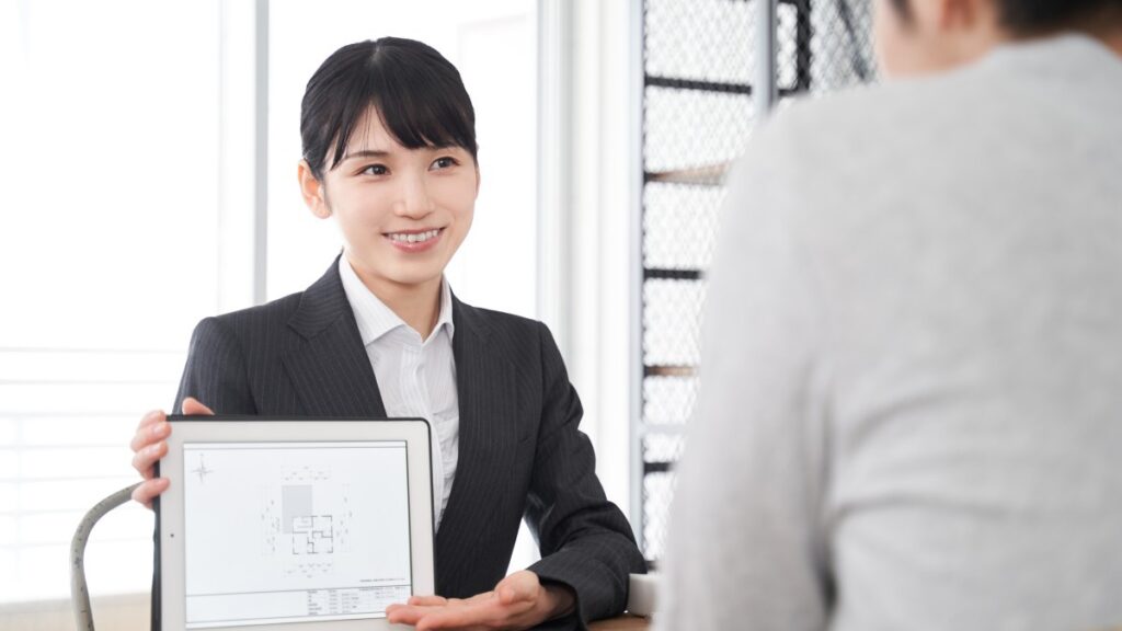 タブレットを使って部屋の説明をする日本人女