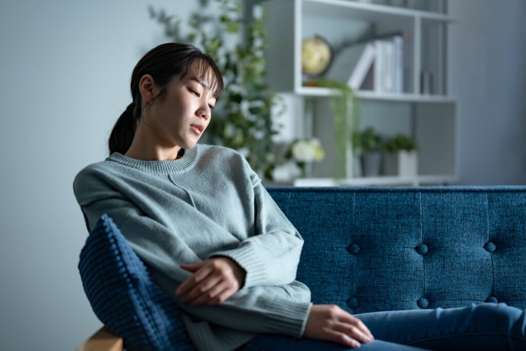 スウェットを着てソファに座って疲れている女性