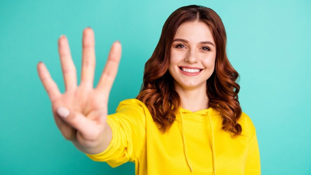 歯を見せて可愛く、魅力的で素敵な陽気な若者の写真。大学で受け取った成績を披露し、青緑色の鮮やかな色の背景に笑顔で輝いている。