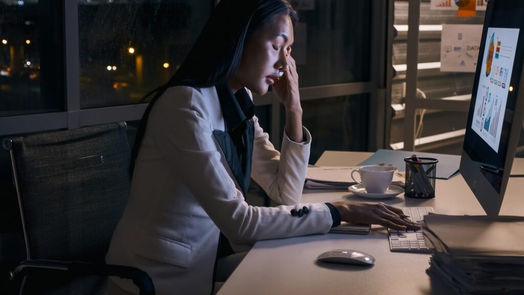 オフィスで残業してストレスを感じている若いアジア人ビジネスウーマン。